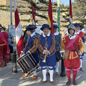 Maltese historical reenactors wearing ceremonial uniforms with drums and flags