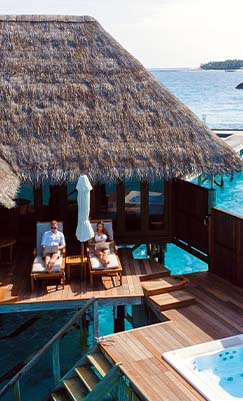 A couple lounging at and overwater bungalow